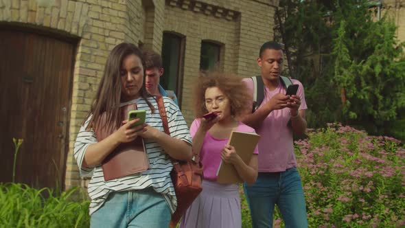 Diverse Students Obsessed with Smartphones Outdoors Leaving Classes