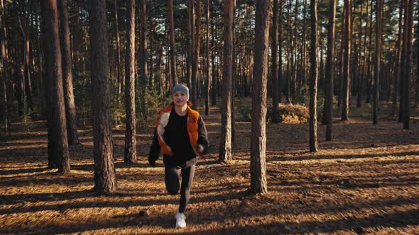 Young Woman Jogging on Trail in Autumn Forest at Sunrise