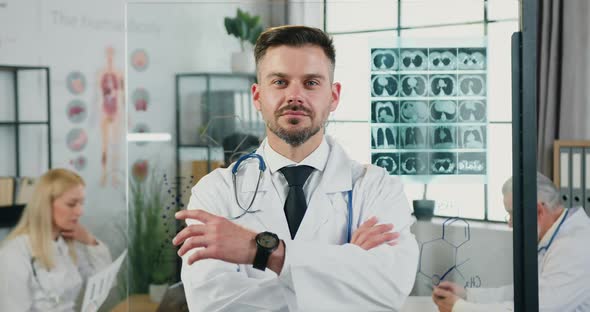 Doctor in Uniform Standing in front of Camera with Crossed Arms in Modern Medical Lab