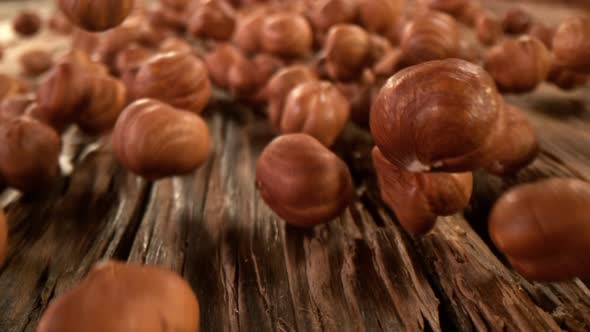 Super Slow Motion Detail Shot of Hazelnuts Rolling Towards on Wooden Background at 1000Fps