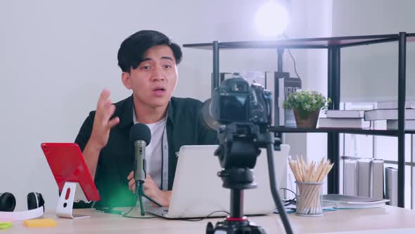 Asian young man live broadcasting coaching something by camera for sharing on social media.