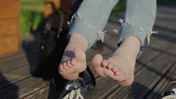 Female resting bare feet on sunny day after taking off heavy shoes