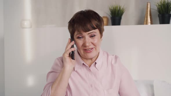 Senior Happy Woman Is Sitting and Talking By Smartphone.