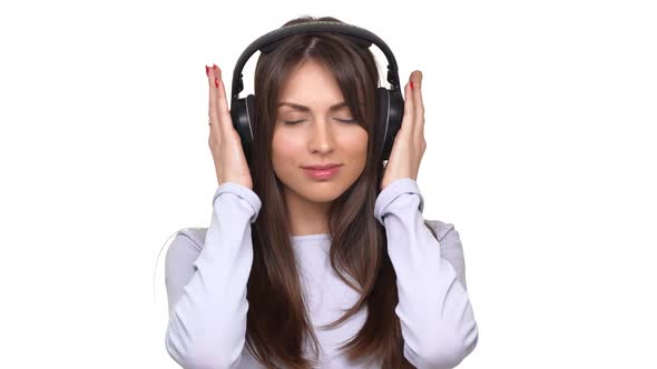 Smiling Beautiful Caucasian Female Listeting Music with Closed Eyes Using Headphones Over White