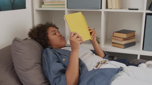 Sleepy Female Student Reading in Bed