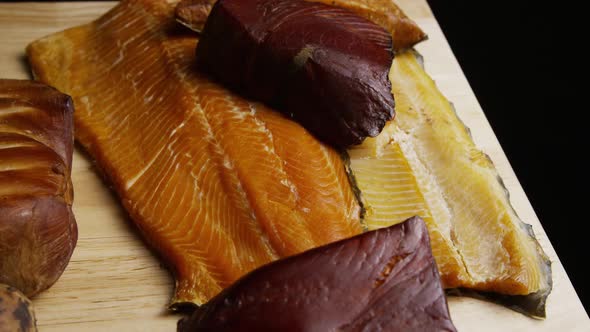 Rotating shot of a variety of delicious, premium smoked meats on a wooden cutting board