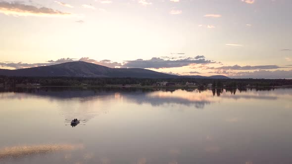 Group of friends rowing a boat in a calm lake during midnight sun in Lapland.