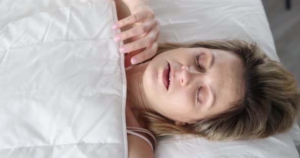 A Woman Wakes Up and Looks Fearfully Under Covers