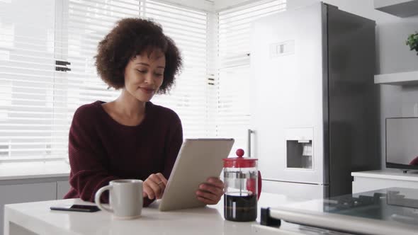 Woman using digital tablet and having a coffee in kitchen