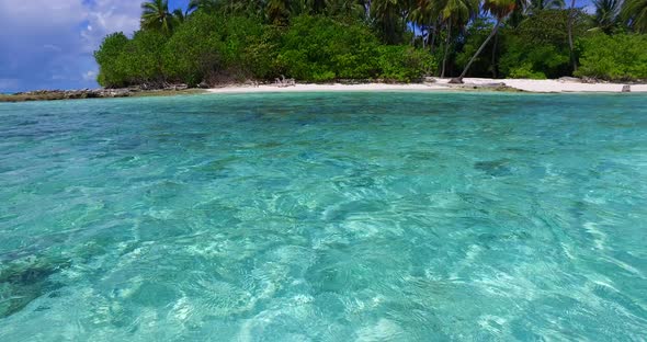 Wide angle fly over travel shot of a white paradise beach and blue water background in colorful 4K