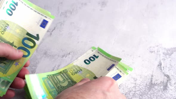 Male Hands Counting European 100 Hundred Euro Money Banknotes and Leave Them on Concrete Background