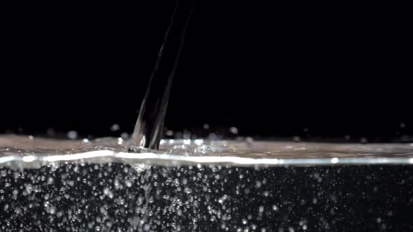 Slow Motion Stream of Water Drops Down in Aquarium on a Black Background