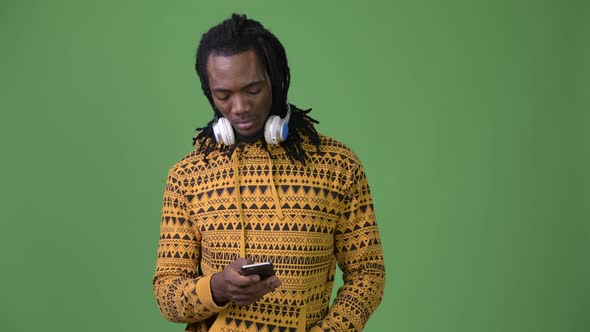 Young Handsome African Man with Dreadlocks Against Green Background