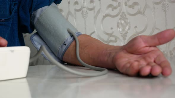 Close-up of the hand of an elderly man measuring blood pressure with a household tonometer while sit