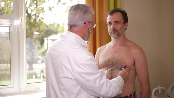 Physician Examining Heart of Man with Stethoscope