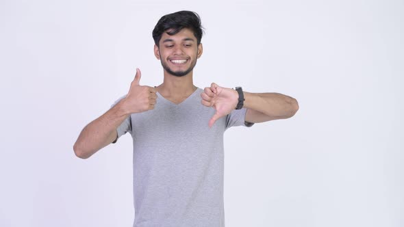 Young Bearded Indian Man Choosing Between Thumbs Up and Thumbs Down