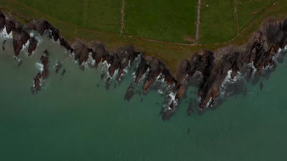 Aerial Birds Eye Overhead Top Down View of Waves Crashing on Jagged Rocky Sea Coast