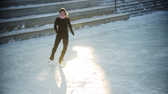 Ice Skating  Young Blonde Woman Figure Skating on the Public Ice Rink in the Morning