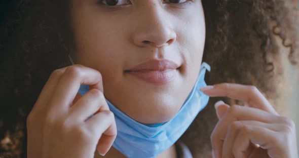 Close-up of Female Hands Putting Mask on Face of African American Young Woman with Curly Black Hair