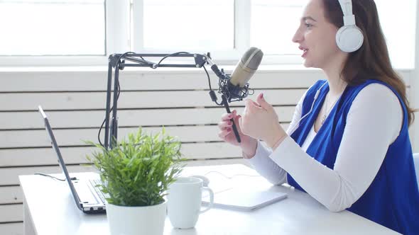 Concept of Streaming and Broadcasting Young Cheerful Girl in the Studio Speaks Into a Microphone