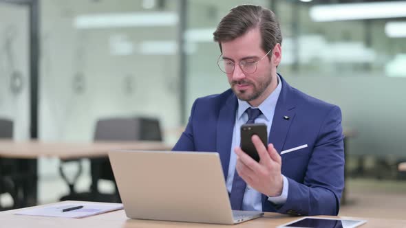 Professional Young Businessman Using Smartphone and Laptop 