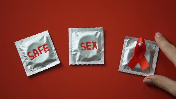 Safe Sex Words and Red Ribbon on Condoms on Red Background Anti AIDS and HIV