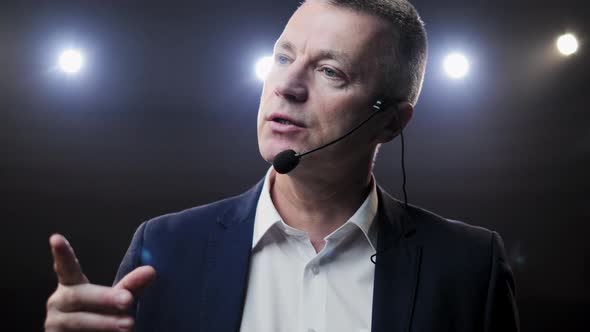 Portrait of Men Speaking Through a Microphone in Dark Conference Hall. Man Talks Into Microphones