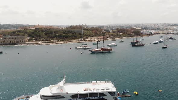 Fly over of harbour from the Tigné Seafront in Sliema city in Malta - Reveal aerial shot