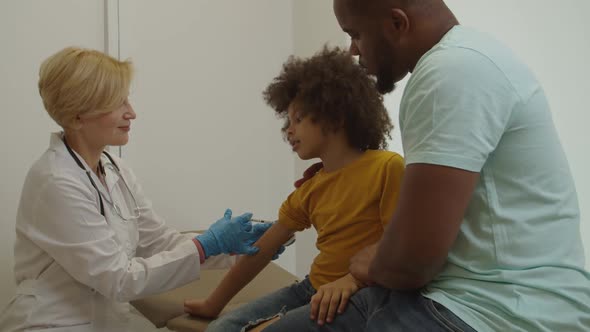 Adorable Preschool Age African American Boy Receiving Vaccination Shot at Hospital