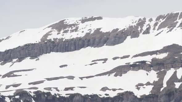 Panning view of snow melting on mountain top.