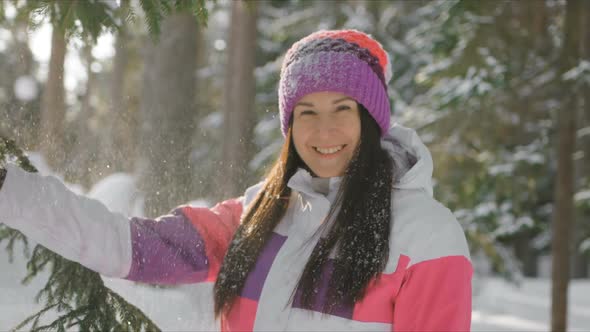 Young Woman Enjoying Sunny Winter Day Throwing Snow Outdoors