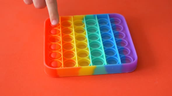 A close-up of a child's hand is playing the popular POP It game.