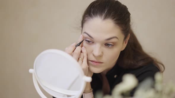 Woman Applying Make Up in Front of a Mirror