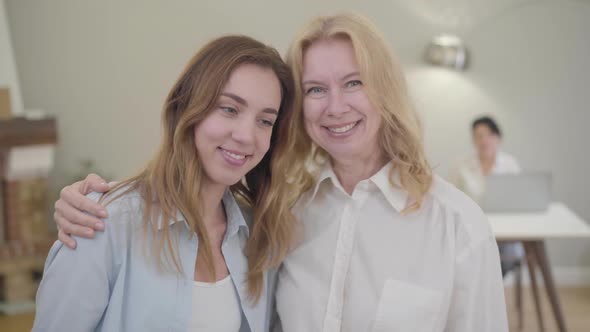 Senior Caucasian Woman Standing with Her Daughter or Daughter-in-law, Looking at Camera and Smiling