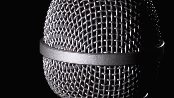 The Microphone Rotates on a Black Background. Dynamic Microphone Grid Spins Close-up