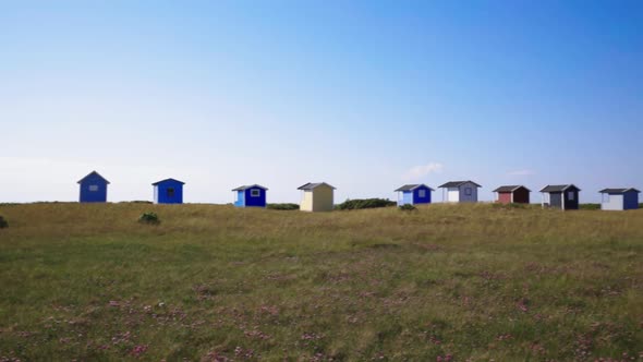 Small cabin boathouses in different colors. Camera pan right handheld