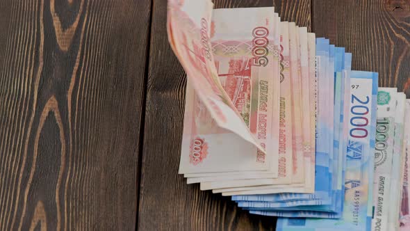 Stack of Russian Rubles Banknotes Dropping on Wooden Surface and Sliding