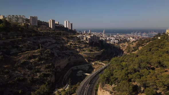 View over a winding road between the hills with the port city of Haifa in the early evening, horzion