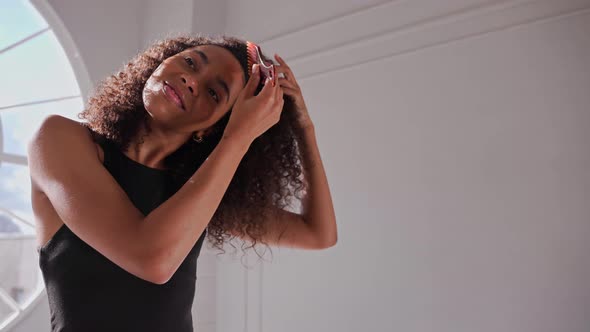 Black Woman Combing Her Afro Hair in Bright White Room