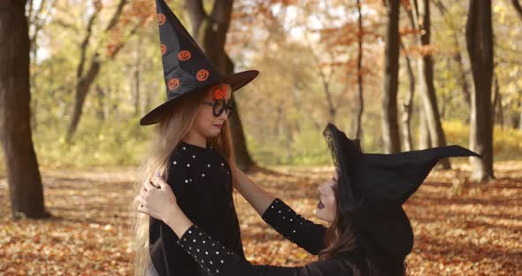 Beautiful Brunette Mom and Cute Little Daughter Looking Like Witches in Special Dresses and Hats in