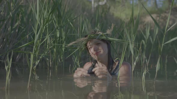 Beautiful Water Maiden with a Wreath on Her Head Smiling Comes Out of the Water