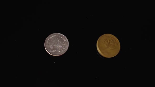 Thai and Indonesian Coins Fall Against a Black Mirror Background in Slow Motion