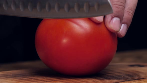 Chef's Hands Cut Fresh Tomato with a Knife on a Wooden Board