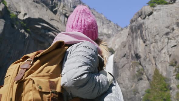 Excited Young Hiker Woman with Tourist Backpack Looking Up at Yosemite Waterfall