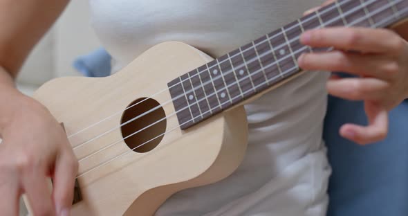 Woman practice ukulele at home