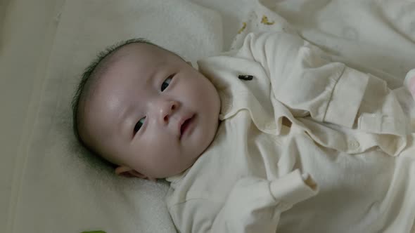 Newborn baby lying in bed and playing.