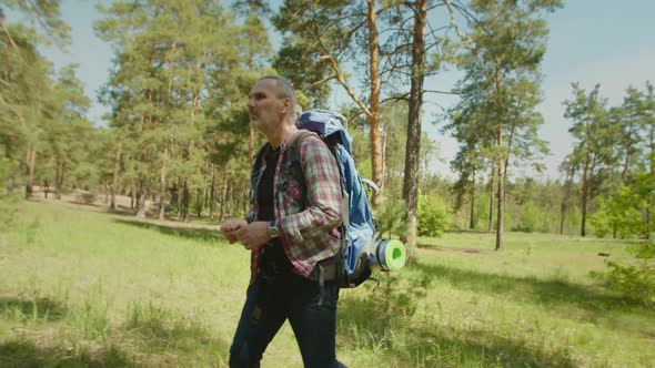 Active Mature Gray Haired Backpacker Man Hiking in Summer Forest