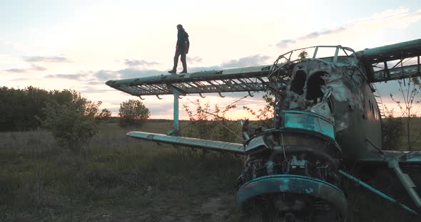 Man Walks on Wing of Maize Airplane with a Disassembled Fuselage, Located in Field with Thick Grass