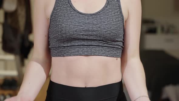 Close up of young woman's torso whilst lifting weights during home workout