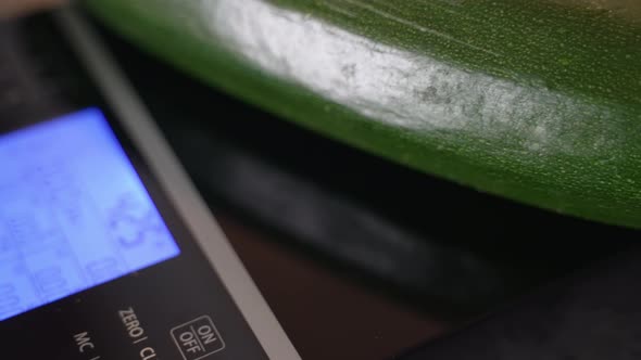 Beautiful Green Cucumber on an Electronic Scale with a Display Illuminated By Artificial Light